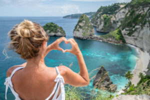 Young woman making heart shape to dreamlike beach from above - Blues and green sand the beautiful mountain shaped on the sea.Travel destinations vacations love people wonderlust concept nature scenics