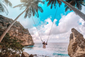 Beautiful girl on swing coconut palms on beach at Daimond beach, Nusa Penida island Bali ,Indonesia